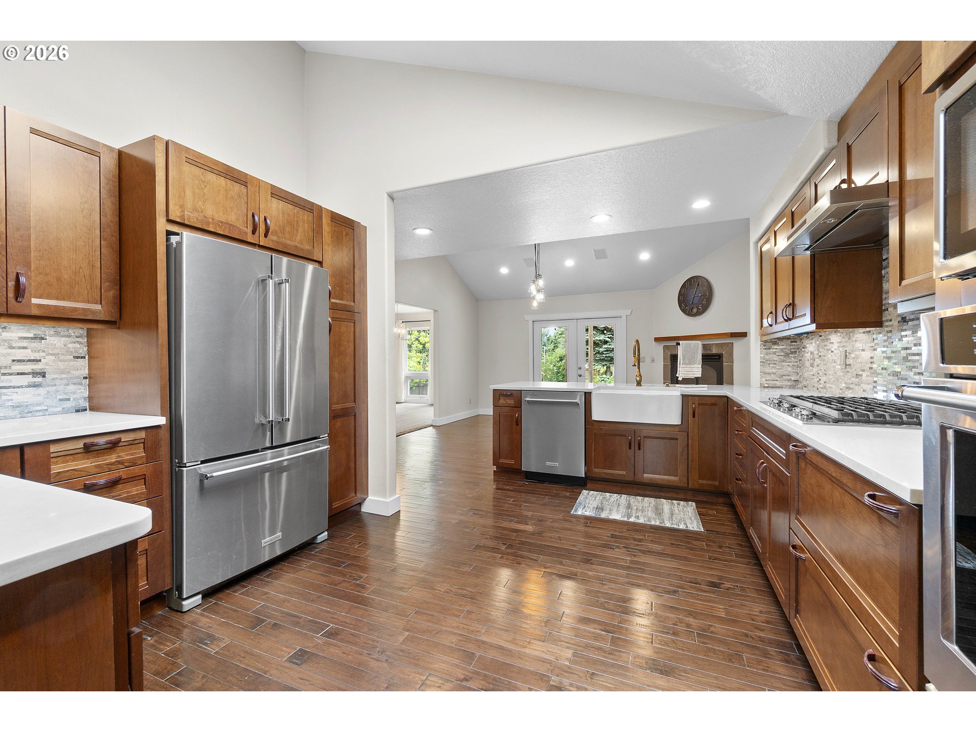 11465 Southwest 92nd Avenue Portland, OR 97223 - Photo 15 of 47 a kitchen with stainless steel appliances kitchen island granite countertop a refrigerator a stove a sink dishwasher and white cabinets with wooden floor