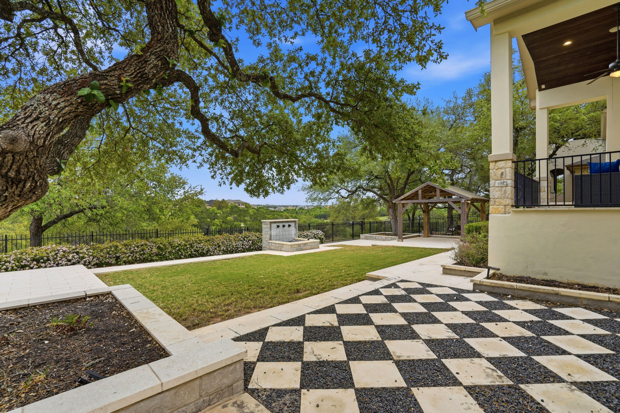 2420 Legend Trail Leander, TX 78641 - Photo 37 of 40 A unique checkerboard patio made of stone pavers and dark gravel adds a touch of whimsy and high-end design to the yard. In the background, a modern stone water feature provides a soothing soundtrack to outdoor gatherings.