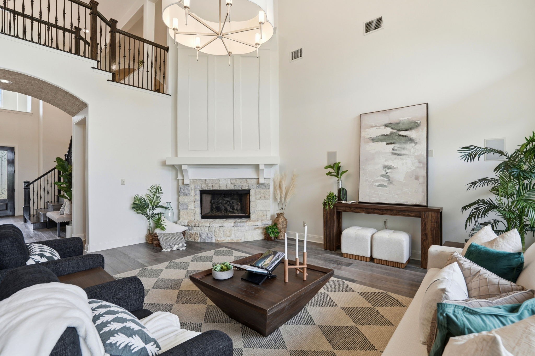2420 Legend Trail Leander, TX 78641 - Photo 6 of 40 Cozy meets grand in the living room, anchored by a stone fireplace. The soft white paneling above the mantel draws the eye upward to the towering ceilings and the dramatic designer chandelier.