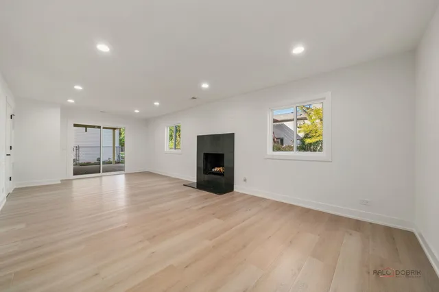 an empty room with wooden floor and kitchen view