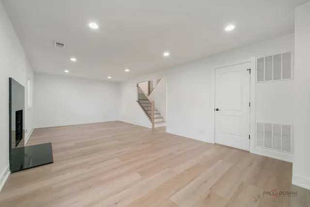 a view of an empty room with wooden floor and a bathroom