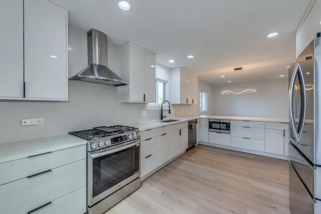 a kitchen with stainless steel appliances a stove a sink and white cabinets