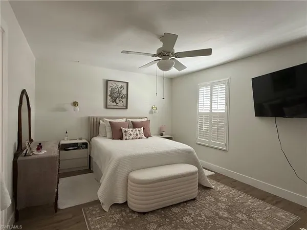 a bedroom with a bed a tv and wooden floor
