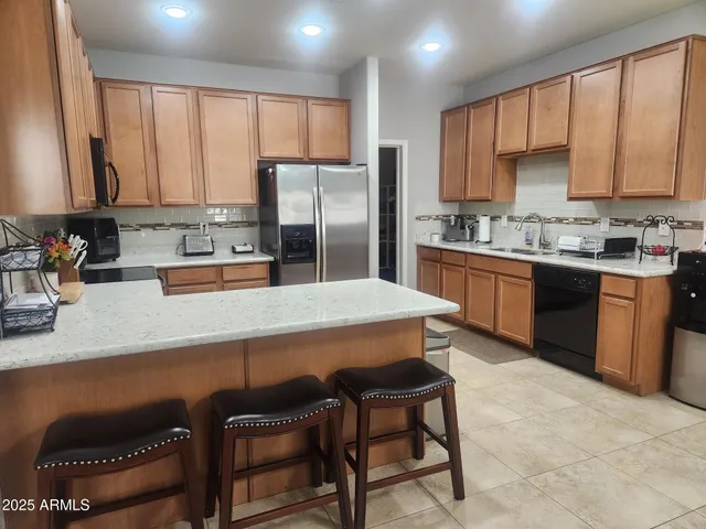 a kitchen with stainless steel appliances granite countertop a stove a sink a microwave a refrigerator and cabinets