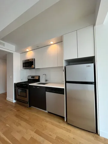 a kitchen with stainless steel appliances granite countertop a refrigerator a stove a sink and a microwave