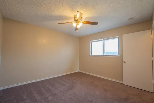 an empty room with a window and a fan