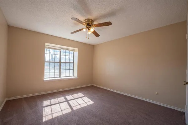 an empty room with windows and fan