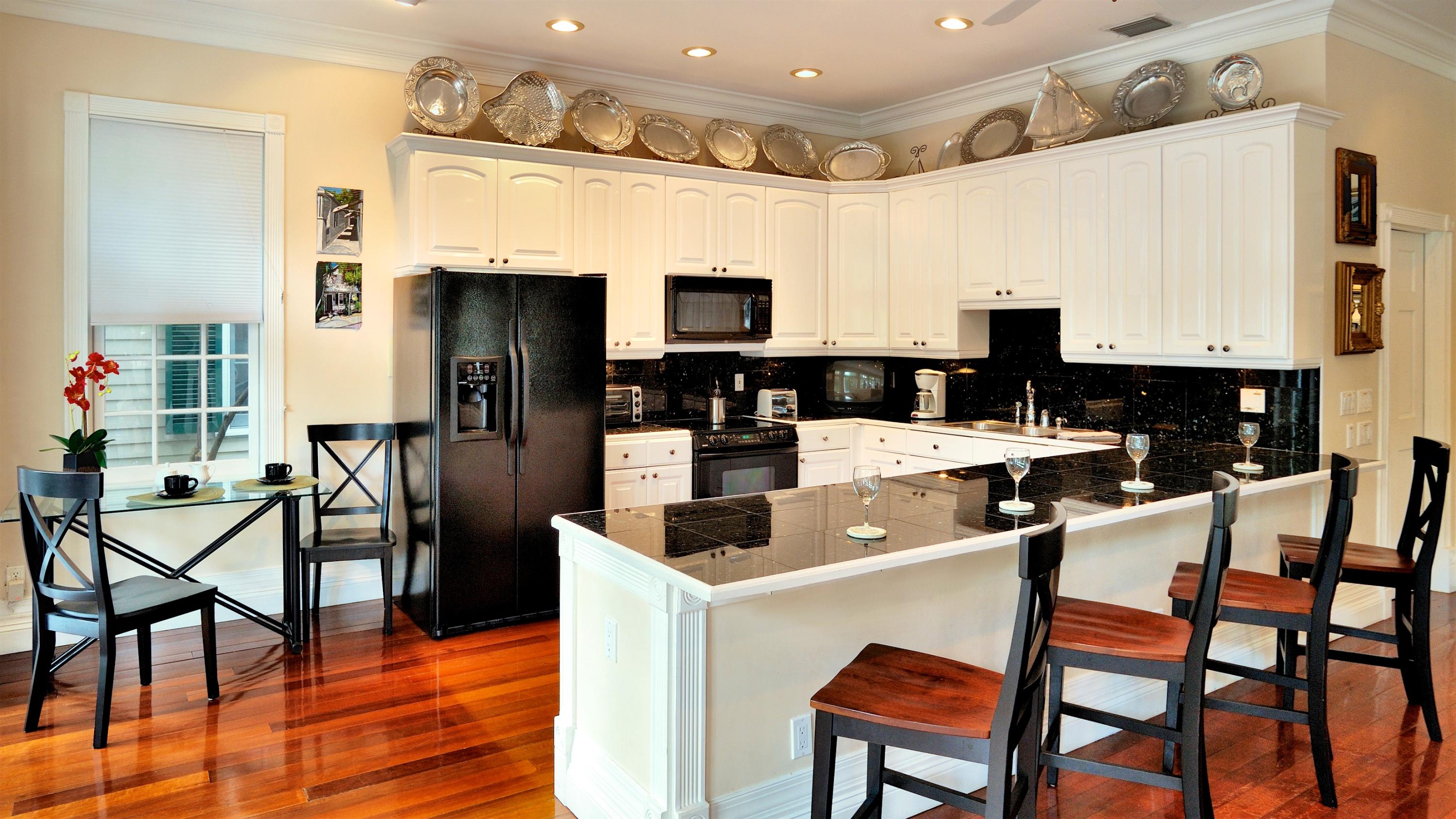 58 Front Street Key West, FL 33040 - Photo 8 of 28 a kitchen with stainless steel appliances kitchen island granite countertop a table chairs and a refrigerator