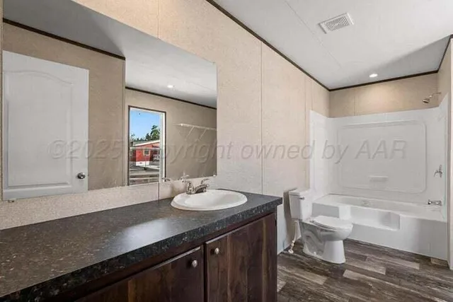 a bathroom with a granite countertop sink a toilet a mirror and bathtub