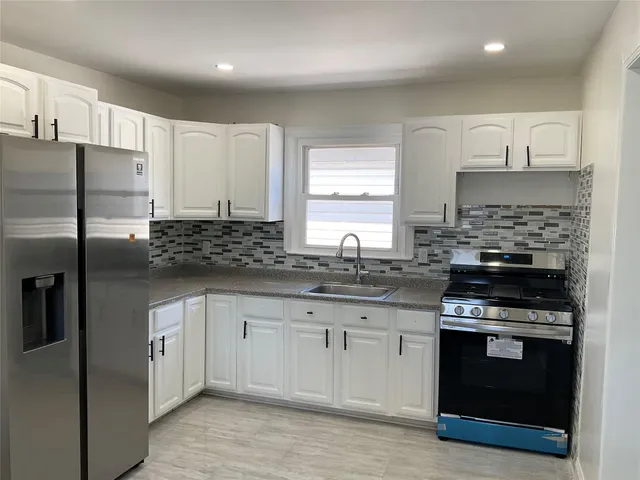 a kitchen with stainless steel appliances granite countertop a stove a sink and a refrigerator