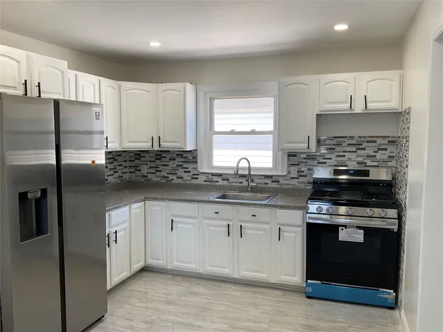 a kitchen with stainless steel appliances granite countertop a stove a refrigerator and a sink