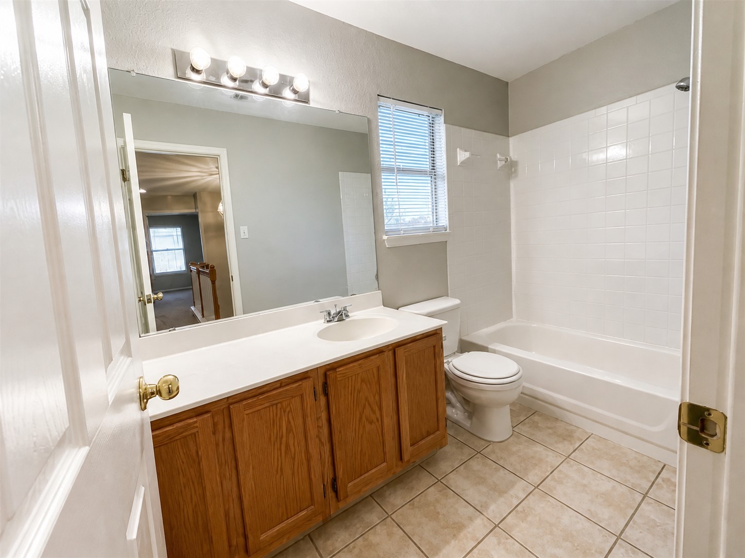 14828 Single Trace Austin, TX 78728 - Photo 20 of 30 Bathroom featuring a wood-finish vanity with an integrated sink, a white countertop, and a vanity mirror with a four-bulb light fixture