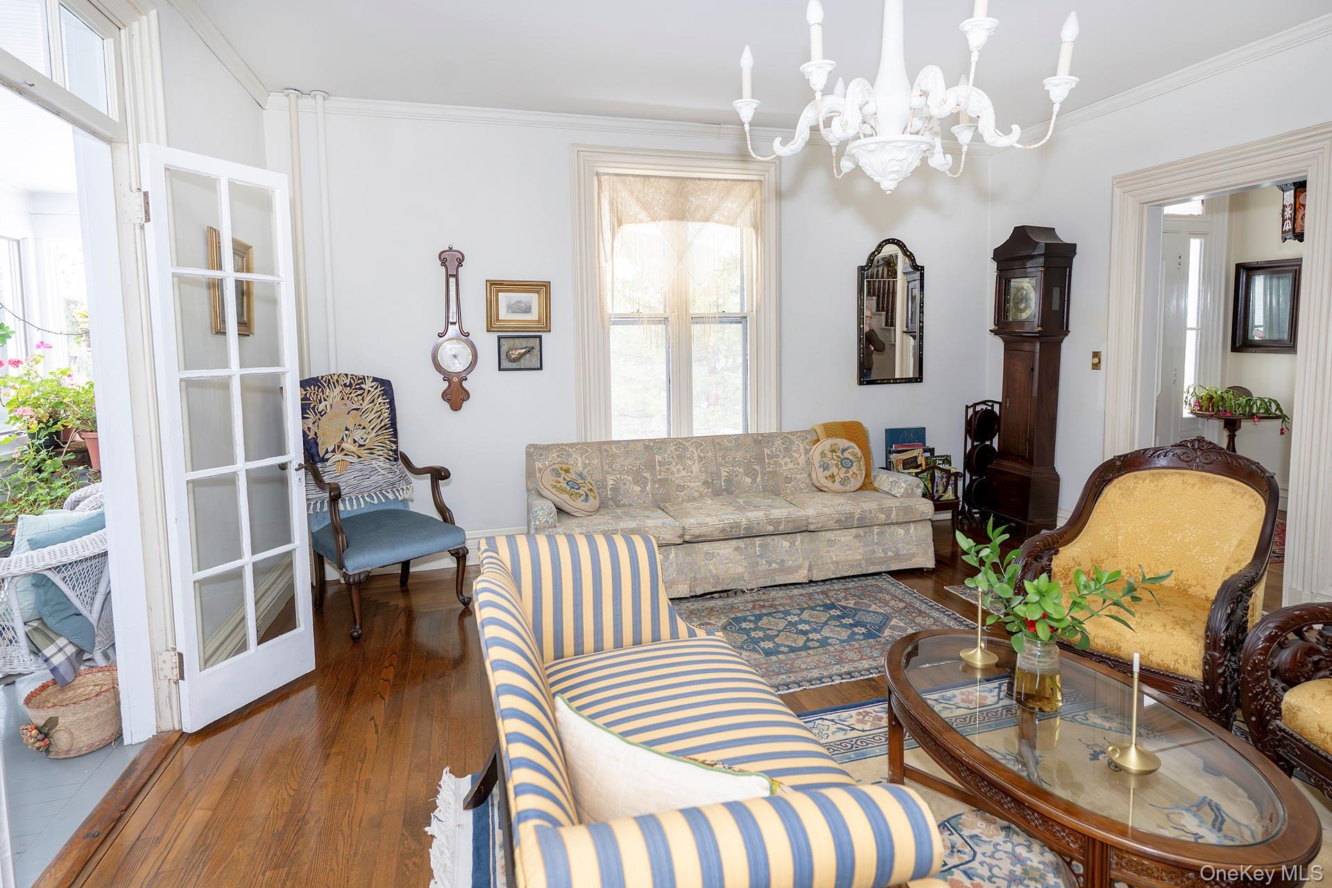 819 Van Wagner Road Poughkeepsie, NY 12601 - Photo 11 of 43 Living area featuring crown molding, a chandelier, healthy amount of natural light, and dark wood-style floors