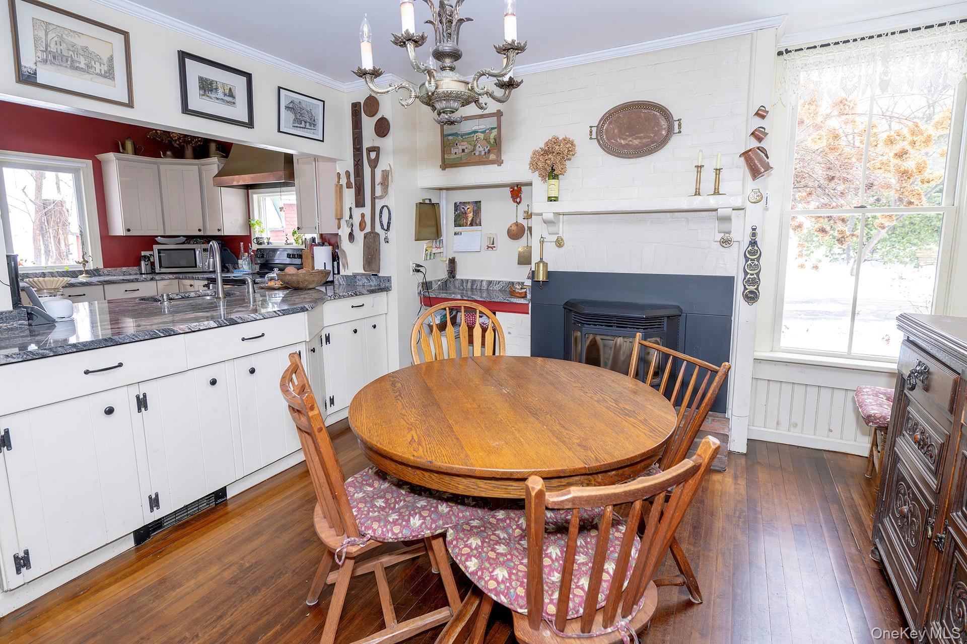 819 Van Wagner Road Poughkeepsie, NY 12601 - Photo 8 of 43 Cozy dining area with a pellet stove, dark wood-style flooring, crown molding, and a chandelier