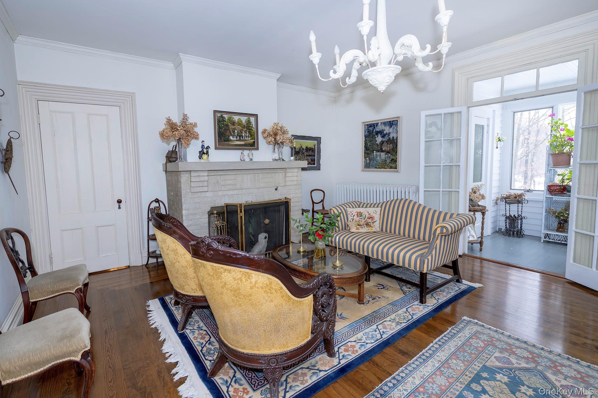 819 Van Wagner Road Poughkeepsie, NY 12601 - Photo 9 of 43 Living area featuring ornamental molding, a fireplace, dark wood finished floors, and a chandelier