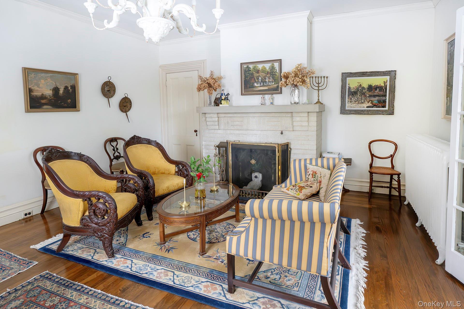 819 Van Wagner Road Poughkeepsie, NY 12601 - Photo 10 of 43 Sitting room with a brick fireplace, dark wood-type flooring, crown molding, radiator heating unit, and a chandelier