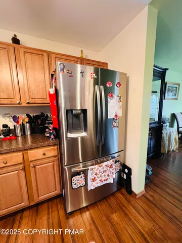 a kitchen with stainless steel appliances a refrigerator and a wooden floor