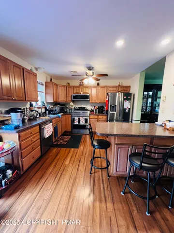 a open kitchen with stainless steel appliances granite countertop a stove top oven a dining table and chairs with wooden floor
