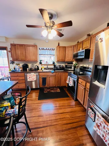 a kitchen with stainless steel appliances a stove a sink dishwasher a dining table and chairs with wooden floor