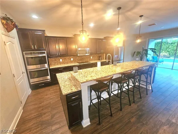 a dining table with stainless steel appliances kitchen island granite countertop wooden floor a dining table and chairs