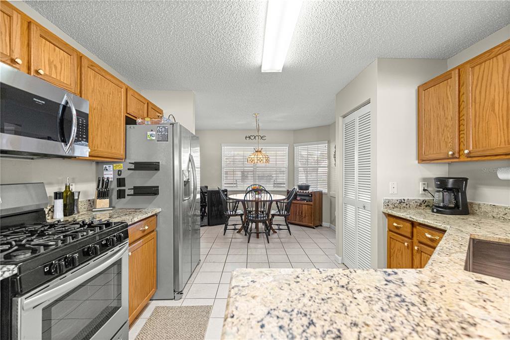 9746 Southwest 96th Street Ocala, FL 34481 - Photo 14 of 57 a kitchen with stainless steel appliances granite countertop a stove top oven a sink a dining table and chairs