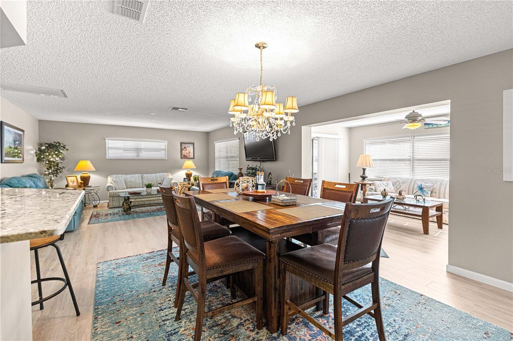 9746 Southwest 96th Street Ocala, FL 34481 - Photo 10 of 57 a dining room with wooden floor a chandelier a wooden table and chairs
