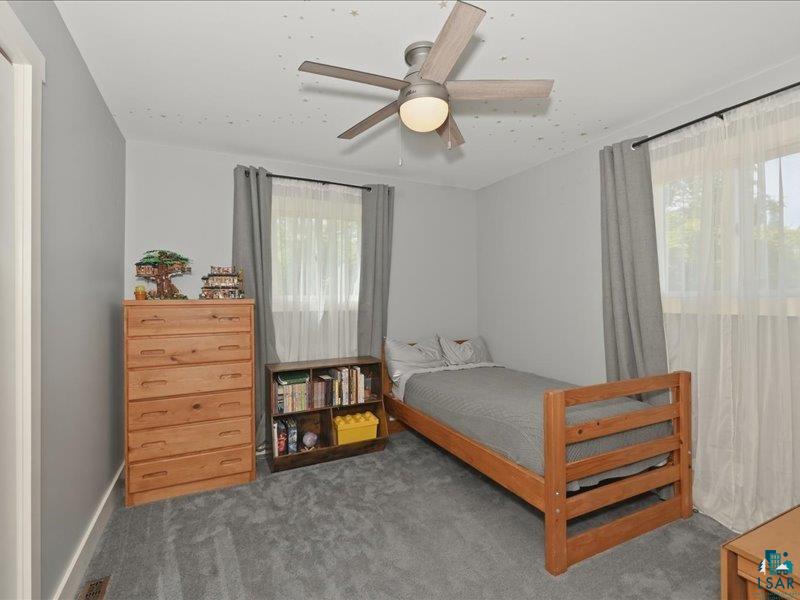 88440 Huron Street Cornucopia, WI 54827 - Photo 20 of 44 Room featuring light gray walls, gray carpeting, and a ceiling fan with a light fixture.
