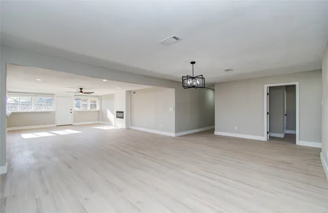 a view of an empty room with window and wooden floor