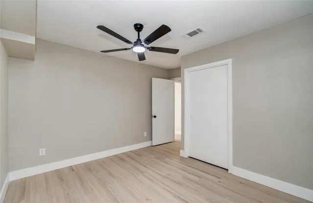 a view of a big room with wooden floor closet and ceiling fan