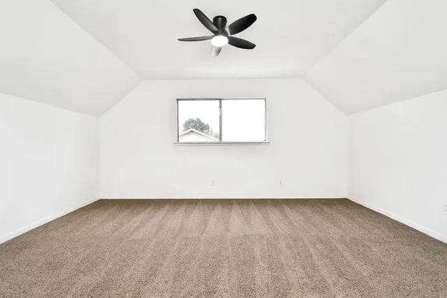 an empty room with a window and a ceiling fan