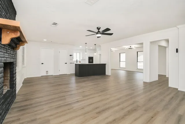 a view of an empty room with a fireplace and wooden floor