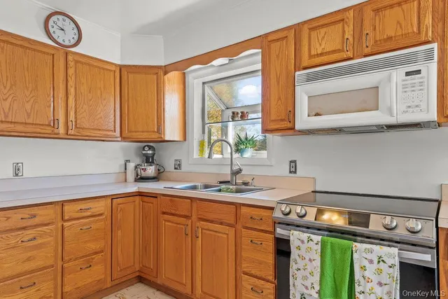a kitchen with stainless steel appliances granite countertop a sink dishwasher a cabinets and a stove next to a window