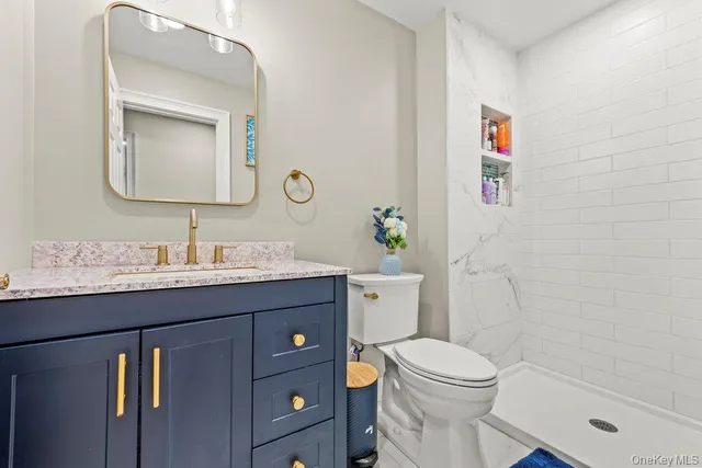 a bathroom with a granite countertop toilet sink and mirror