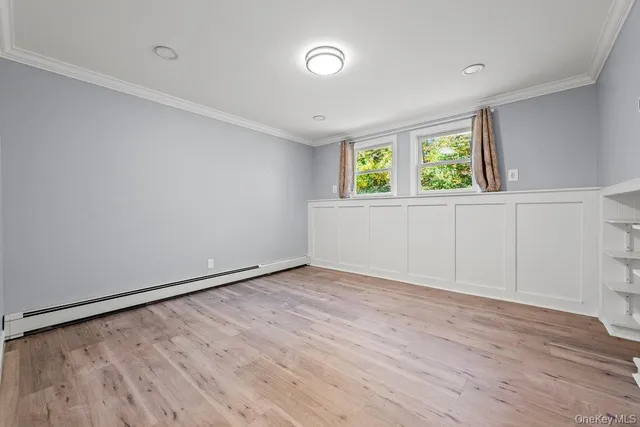 a view of an empty room with wooden floor and window