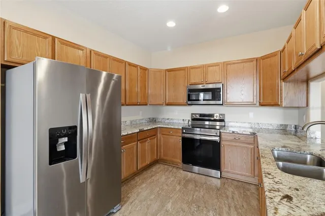 a kitchen with granite countertop a refrigerator stove and microwave