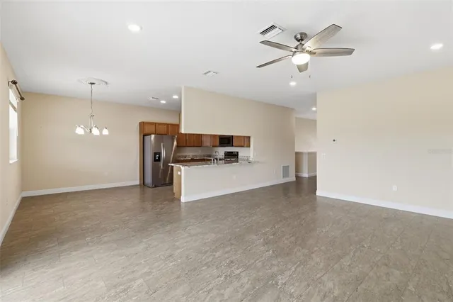 an empty room with chandelier fan and windows