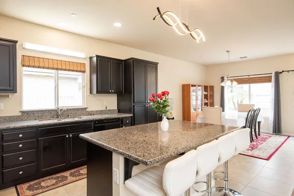 a kitchen with granite countertop kitchen island stainless steel appliances a sink stove and table