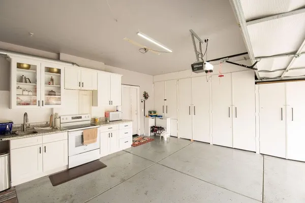 a large white kitchen with a sink and dishwasher a refrigerator with white cabinets