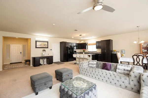 a living room with furniture kitchen view and a chandelier