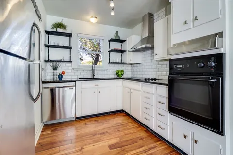 a kitchen with stainless steel appliances granite countertop a sink a stove a microwave a refrigerator and cabinets