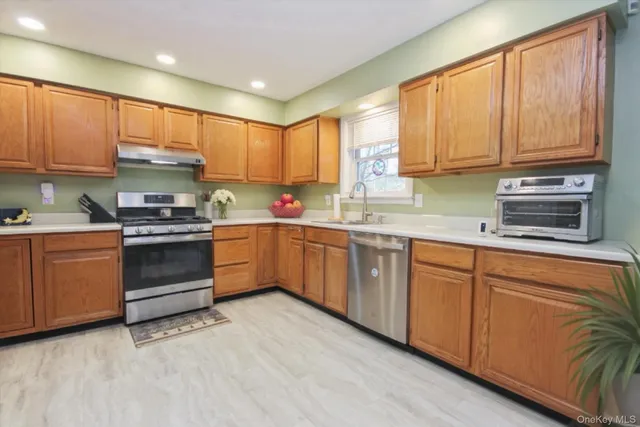 a kitchen with stainless steel appliances granite countertop a stove a sink and a microwave