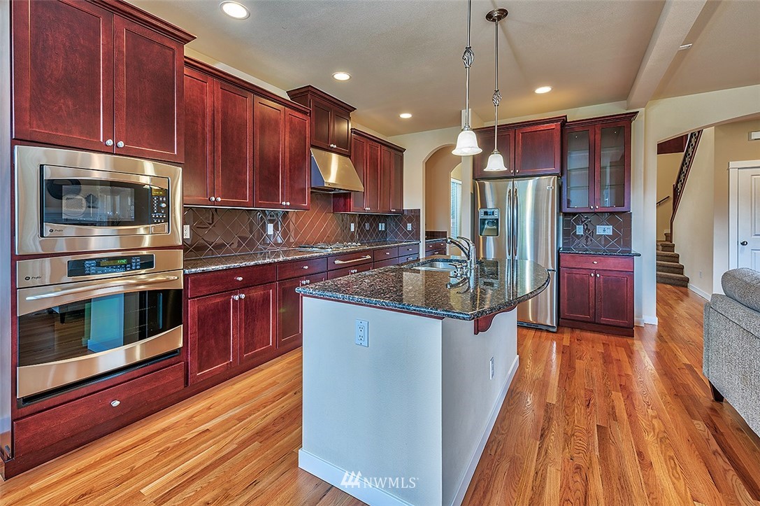 4201 222nd Place Southeast Bothell, WA 98021 - Photo 6 of 25 a kitchen with stainless steel appliances wooden floors wooden cabinets and a sink