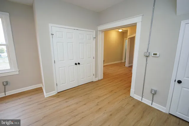 a view of an empty room with wooden floor and closet