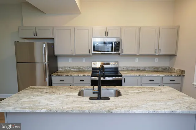 a kitchen with a refrigerator a stove a sink and a white cabinets