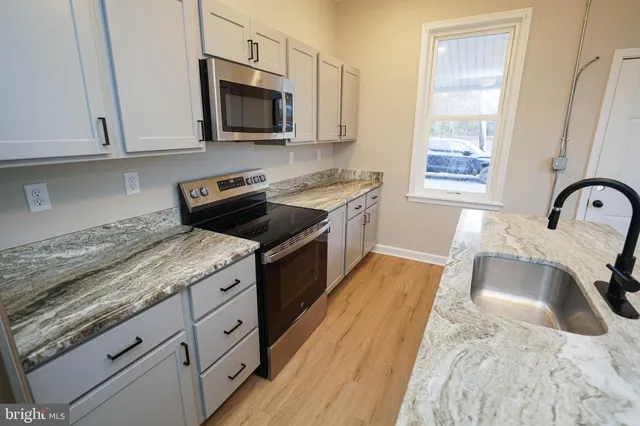 a kitchen with stainless steel appliances granite countertop a sink stove and microwave
