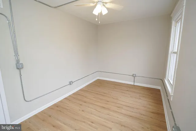 a view of empty room with wooden floor and fan