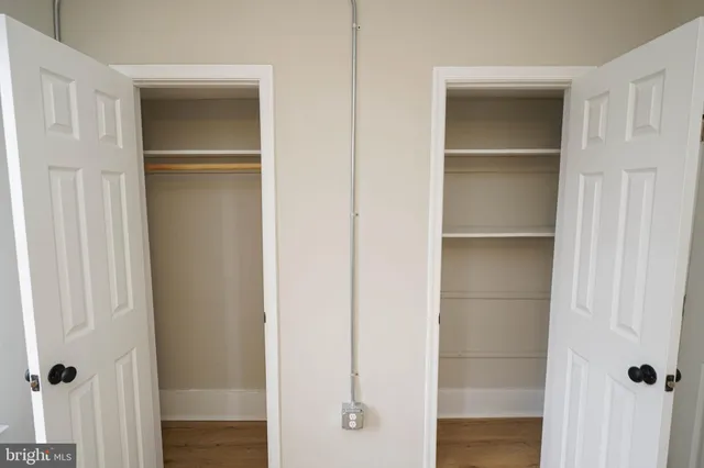 an empty room with wooden floor cabinet and windows