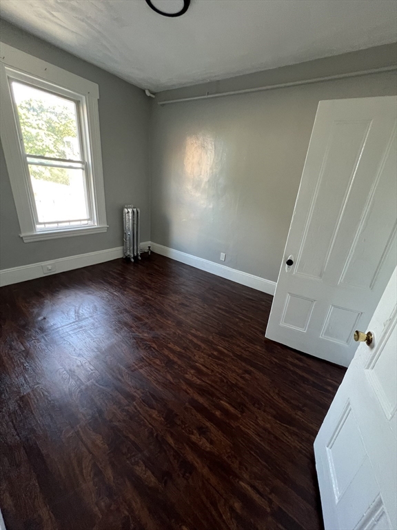 64 Hollis Street, Unit 16 Framingham, MA 01702 - Photo 3 of 6 an empty room with wooden floor and windows