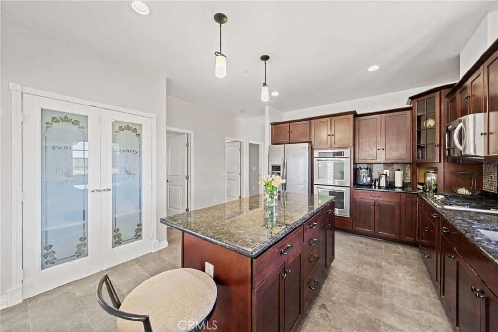 13560 Sego Road Agua Dulce, CA 91390 - Photo 22 of 75 a kitchen with kitchen island a refrigerator a stove a sink and white cabinets with wooden floor