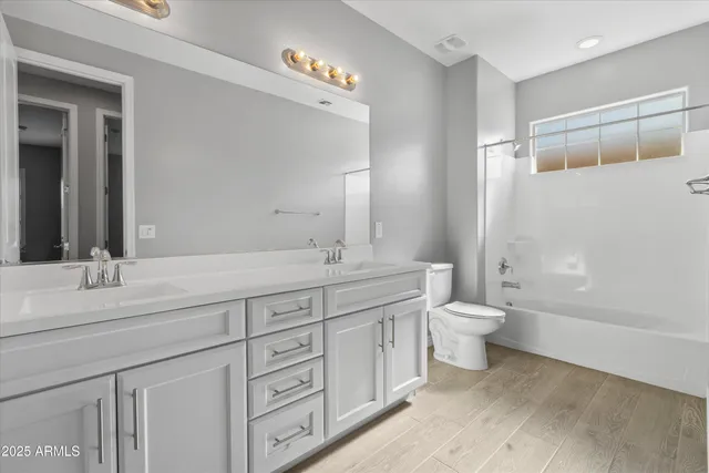 a bathroom with a double vanity sink a toilet and a mirror